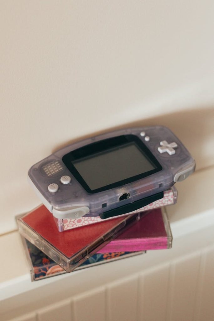 Close-up of a retro gaming console placed atop colorful cassette tapes, evoking nostalgia.